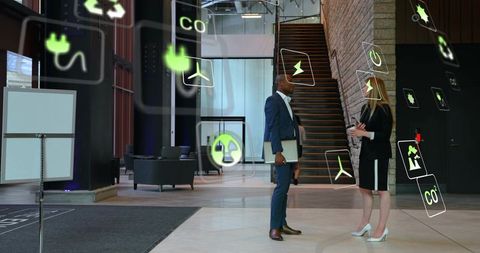 Discussing sustainable energy strategy in modern corporate lobby with floating eco icons