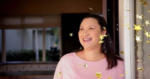 Smiling mature woman standing in doorway with gold star overlays and joyful expression