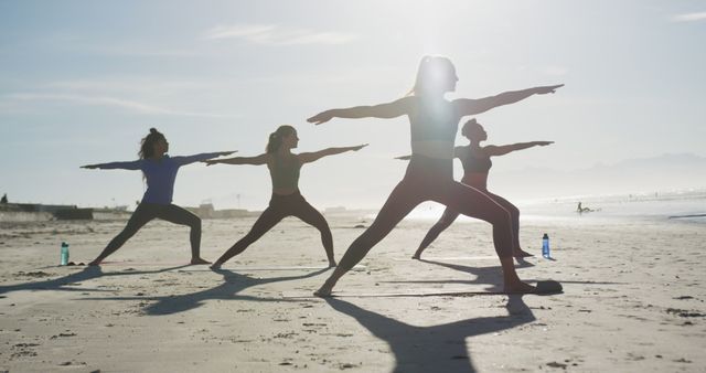 Group of women practicing yoga poses on beach at sunrise, creating serene and empowering environment. Perfect for promoting fitness, wellness, outdoor activities, healthy lifestyle, teamwork, and peacefulness.
