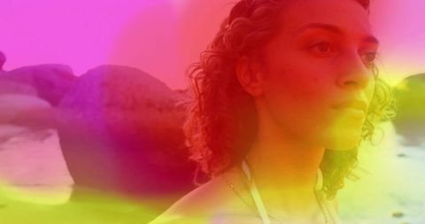 Gazing young woman at rocky beach with colorful gradient overlay, contemplative profile