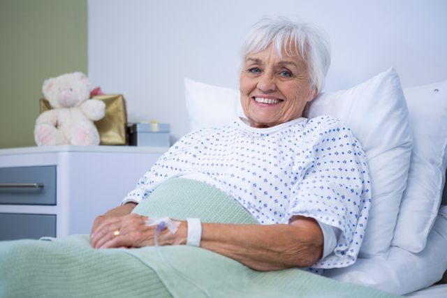 Portrait of smiling senior patient on bed in hospital