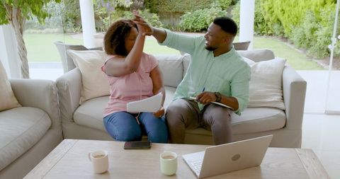 Happy couple celebrating success with documents at home