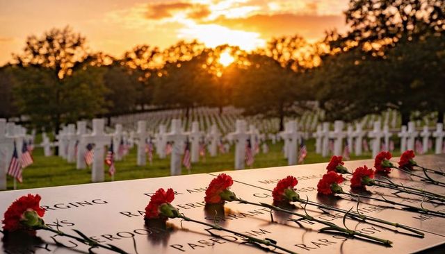 Sunset casting golden light over military cemetery with carnations on engraved memorial