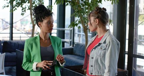 Two Colleagues Discussing Project in Modern Urban Office Lounge Holding Wallet and Phone