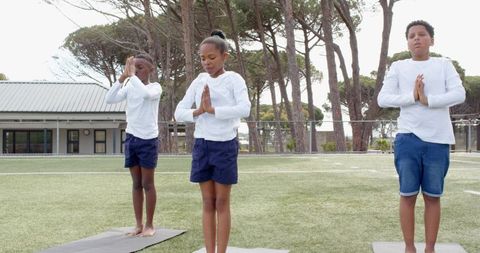 Diverse Children Practicing Yoga Outdoors on School Turf
