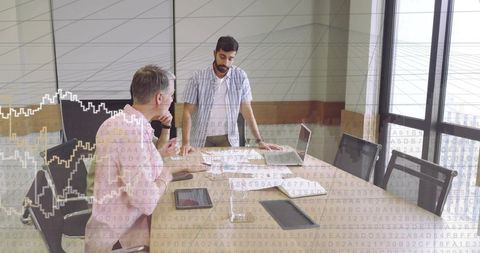 Business leader guiding team through data review with laptop and charts in boardroom