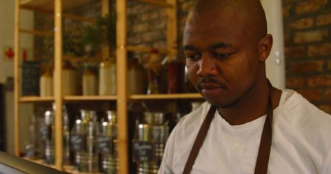 Attentive male staff engaged with computer at grocery counter