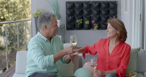 Happy Mature Couple Toasting with White Wine on Terrace