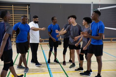 High school boys volleyball team gathering with coach for pre-game huddle and motivation