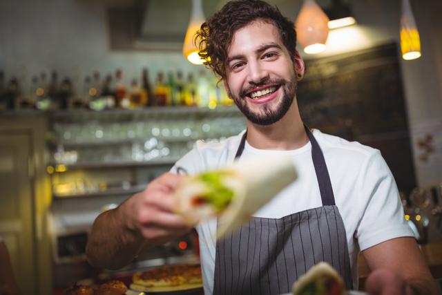 Portrait of waiter holding vegetable roll in cafÃ©