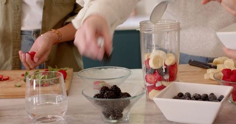 Diverse Friends Preparing Berry Smoothie in Modern Kitchen