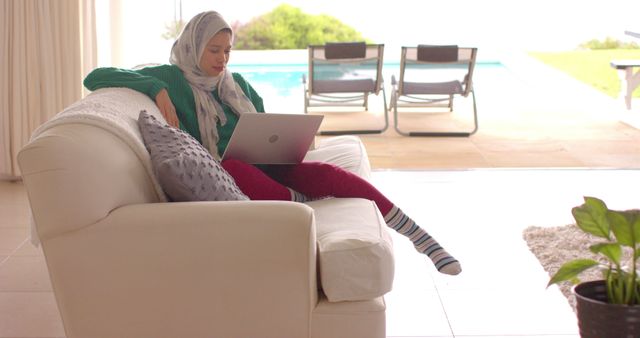 Woman Wearing Hijab Relaxing and Using Laptop on Sofa at Home - Download Free Stock Images Pikwizard.com