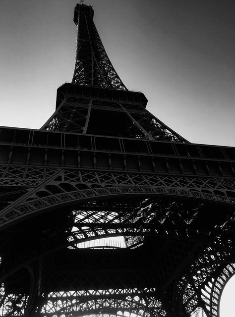 The Eiffel Tower, captured in a stunning black and white photograph, highlights its intricate steel structure from a unique upward perspective. This compelling image encapsulates the grandeur and architectural brilliance of this iconic landmark. Ideal for travel blogs, architectural showcases, posters, and décor that exudes elegance and majesty.