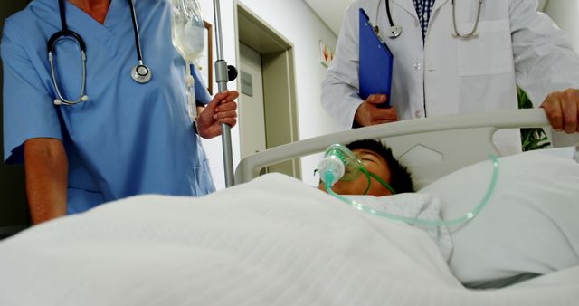A diverse team of healthcare professionals, including a nurse and a doctor, attends to a patient in a hospital bed, with copy space. The patient appears to be receiving oxygen support, indicating a medical treatment scenario.