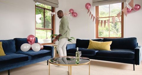 Man Decorating Living Room with Balloons for Home Celebration