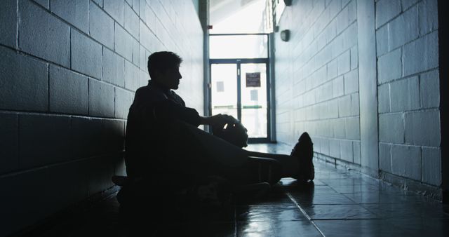 Silhouetted Person Sitting Alone in Dimly Lit Hallway - Download Free Stock Images Pikwizard.com
