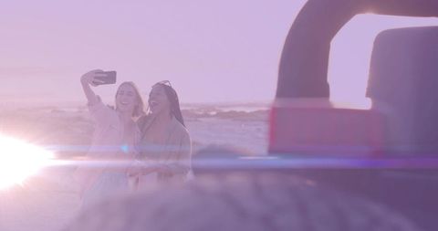 Two Friends Taking Selfie at Sunset on Sandy Beach Side