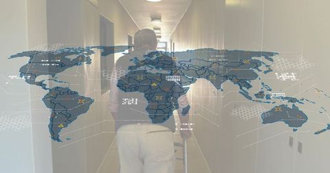 Senior man walking with cane along care corridor with global map overlay for eldercare tech