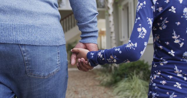 Midsection of back of biracial father and daughter holding hands in garden. Lifestyle, family, togetherness, childhood and domestic life, unaltered.