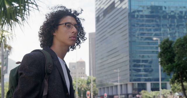 Pensive Young Professional Stands in Urban Setting with Skyscraper Background - Download Free Stock Images Pikwizard.com