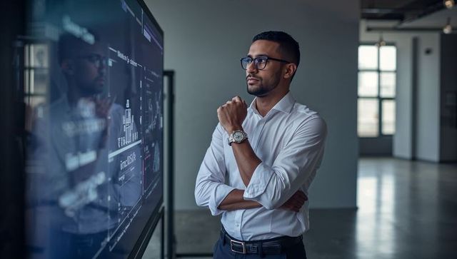 Asian professional analyzing interactive data dashboard on touchscreen in loft workspace