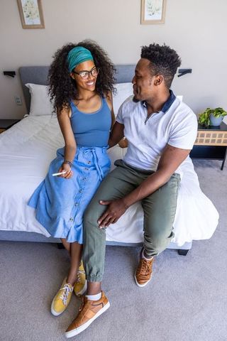 African american couple celebrating positive pregnancy test, sharing tender moment on bed