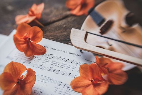Sheet music with orange flowers and violin on rustic surface