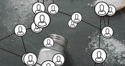 Tipped salt shaker scattering salt granules on dark tabletop with social network overlay