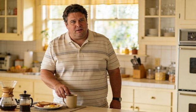 Man standing in cozy sunny kitchen touching coffee mug at breakfast with eggs and chemex