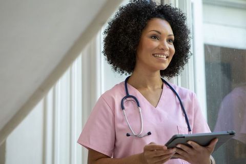 African American Nurse in Pink Scrubs Using Tablet