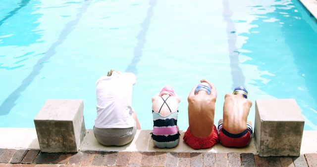 Group of children sitting poolside, dressed in swimsuits and swim caps. Ideal for concepts related to swimming, summer activities, children’s sports, swim lessons, and outdoor recreation.