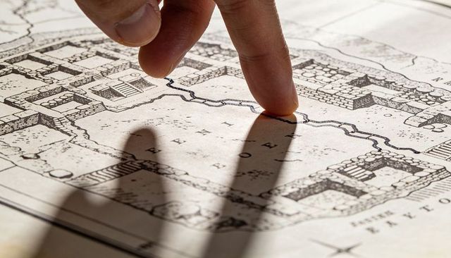 Finger tracing hand-drawn map route casting long shadow for navigation and exploration