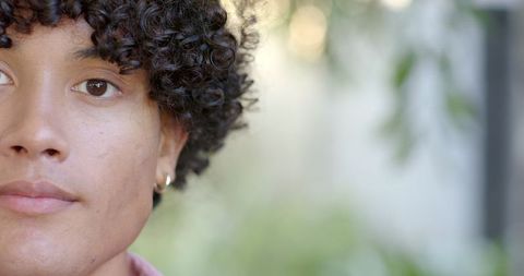 Youthful elegance: man posing outdoors with curly hair and hoop earring