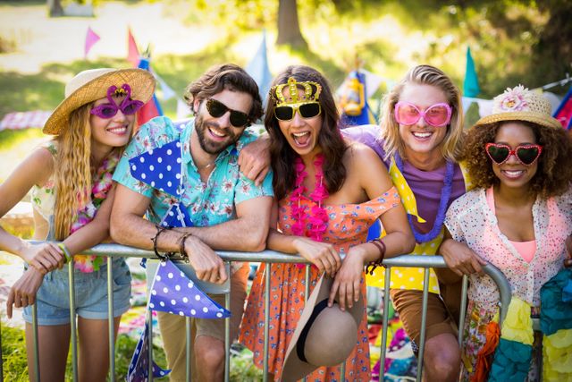 Group of friends standing together, enjoying a sunny day at an outdoor festival. They are dressed in colorful, casual summer attire, wearing sunglasses and smiling. Perfect for use in advertisements, social media posts, or articles about friendship, summer activities, festivals, and outdoor events.