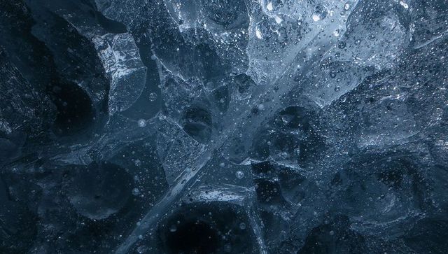 Revealing fractured blue ice macro texture with trapped air bubbles and crystal cracks