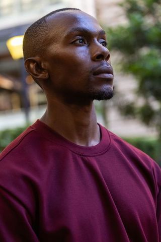 African american man gazing upward wearing maroon sweatshirt in urban plaza serene portrait