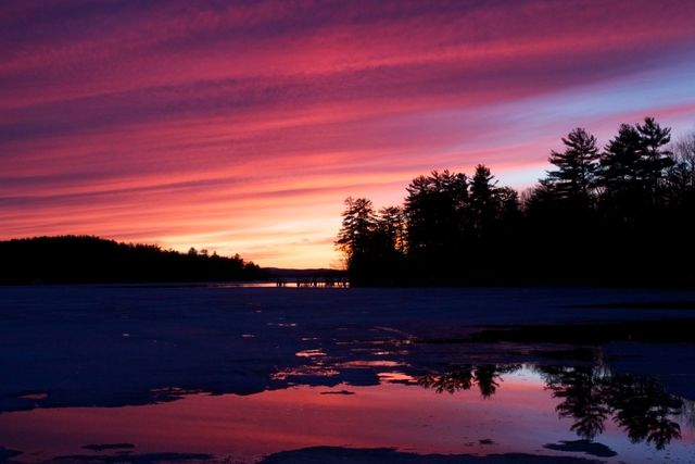 Vibrant Winter Sunset Over Frozen Lake with Pine Tree Silhouettes - Download Free Stock Photos Pikwizard.com