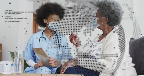 Home visit nurse consulting elderly patient wearing masks holding tablet for telemedicine