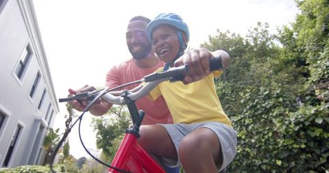 Father Guiding Son Learning to Ride Bicycle in Sunny Garden - Download Free Stock Images Pikwizard.com