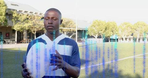 Rugby player holding ball on campus pitch with binary code overlay, meditating before match