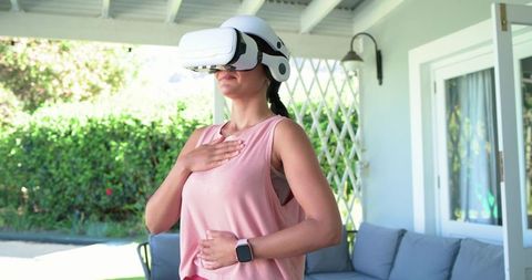 African American woman practicing VR breathwork on porch with smartwatch and garden sunlight
