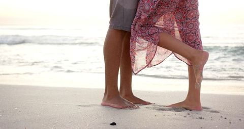 Romantic beach embrace at sunset with barefoot couple