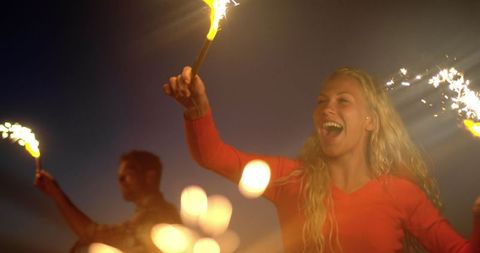 Joyful Couple Celebrating with Sparklers on Beach at Dusk
