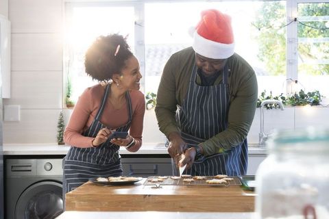 African american couple decorating christmas cookies in sunlit kitchen