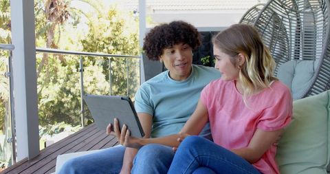 Young Couple on Porch Enjoying Digital Tablet Interaction