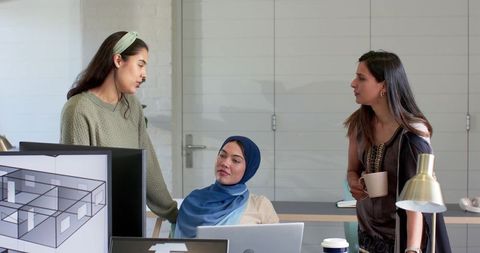 Diverse women collaborating on architectural floor plans in modern coworking office