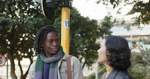 Diverse friends talking on city sidewalk near yellow pole 15 wearing scarves and jackets