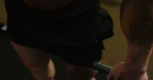 Close-up view of person lifting barbell weights, showcasing muscular arms and hands gripping the barbel. Useful for promoting fitness routines, workout programs, strength training, gym memberships, and health and wellness content.