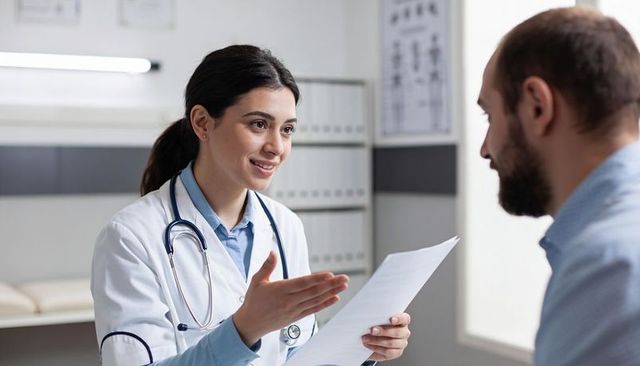 Female physician explaining test results to male patient during clinic consultation