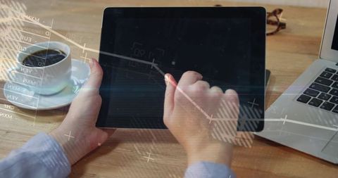 Business tapping tablet touchscreen with financial charts overlay on desk workspace